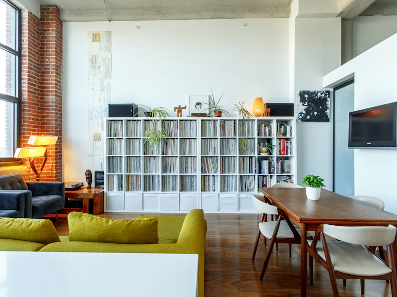 Loft com parede de tijolo, estante branca e sofá verde